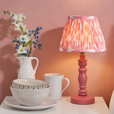 Vibrant table lamp with satin pink clay base and coral pink ikat pattern pleated shade.